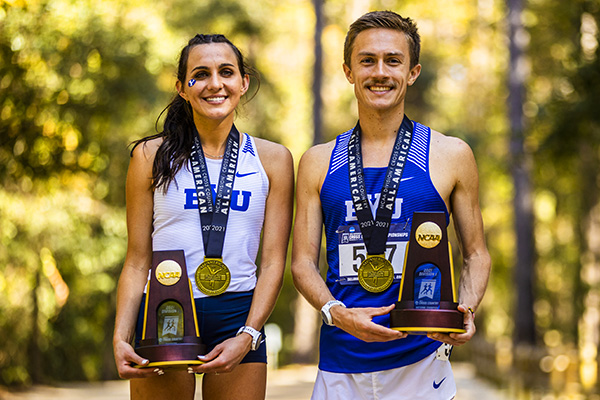 Whittni Orton and Conner Mantz wearing cross country gear and medals and holidng trophies.